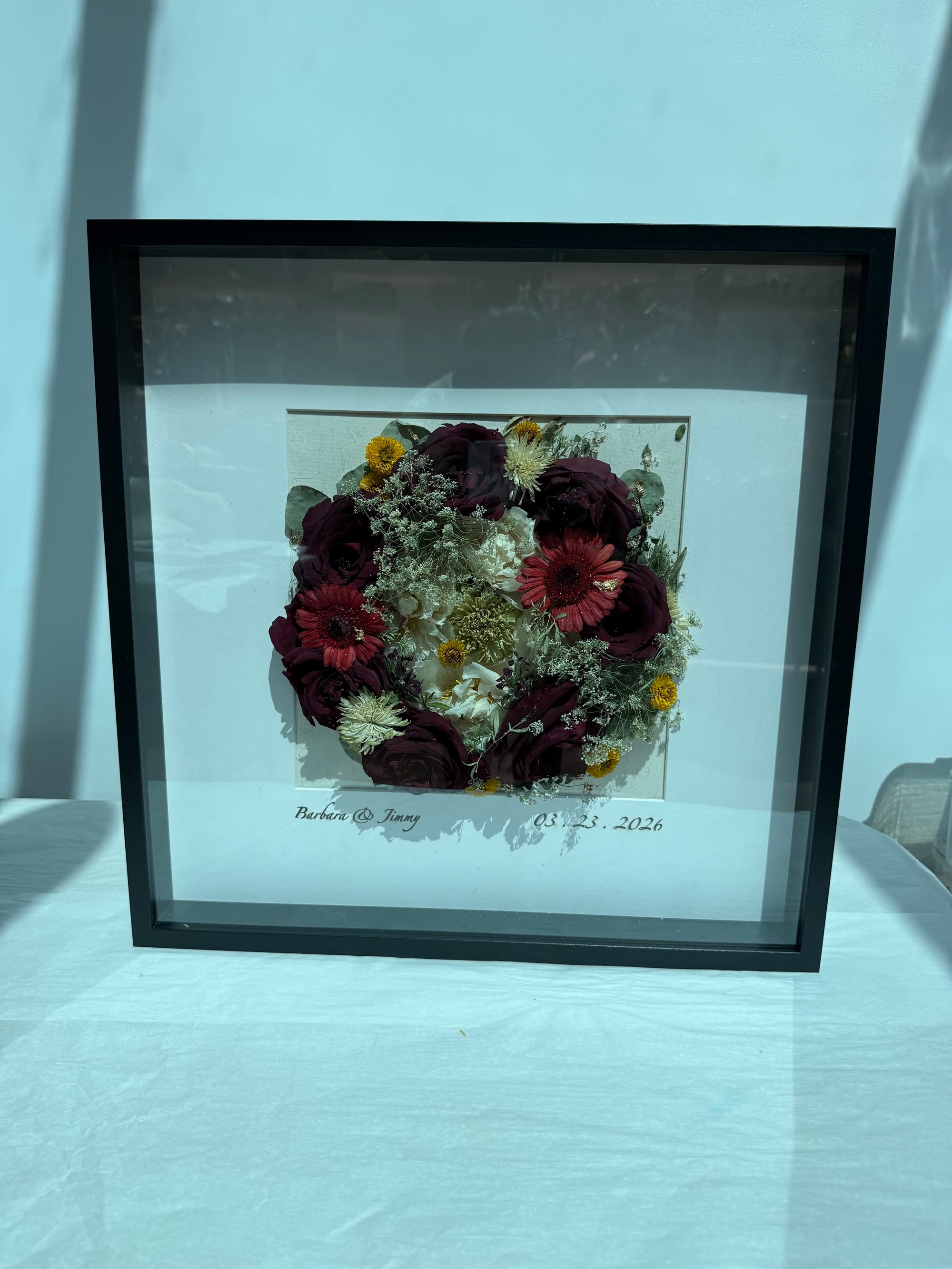 Pressed wedding flowers in a dark frame